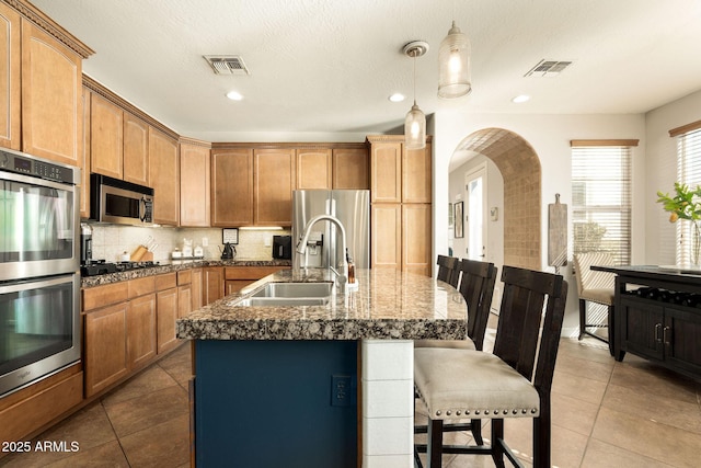 kitchen featuring a kitchen bar, visible vents, appliances with stainless steel finishes, and a sink