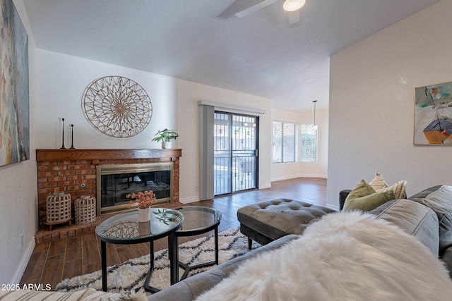 living room with dark hardwood / wood-style flooring, ceiling fan, and a fireplace