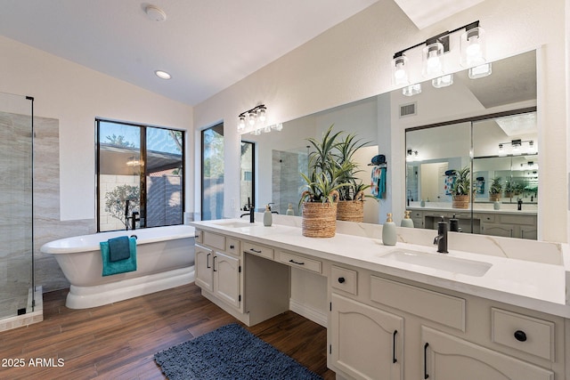 bathroom with vaulted ceiling, vanity, a bathtub, and wood-type flooring