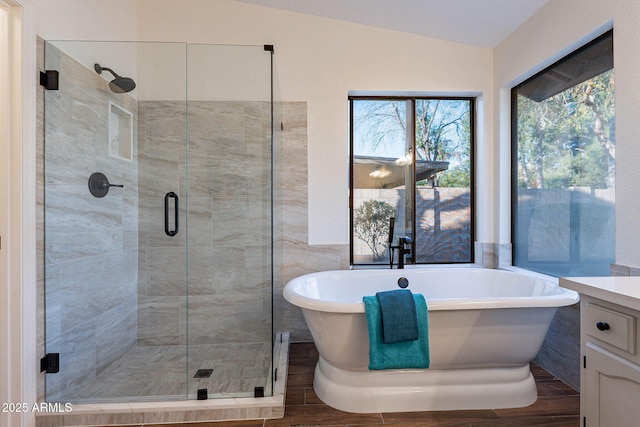 bathroom with plus walk in shower, vaulted ceiling, wood-type flooring, and vanity