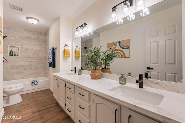 full bathroom with hardwood / wood-style flooring, vanity, toilet, and tiled shower / bath combo