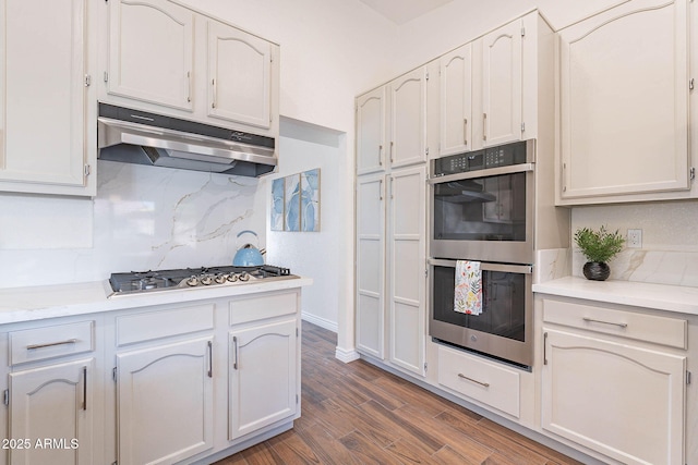 kitchen with backsplash, stainless steel appliances, dark wood-type flooring, and white cabinets