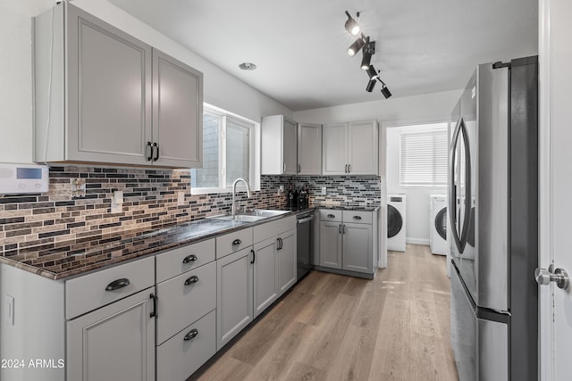 kitchen featuring light wood-type flooring, stainless steel appliances, washer and clothes dryer, and gray cabinetry