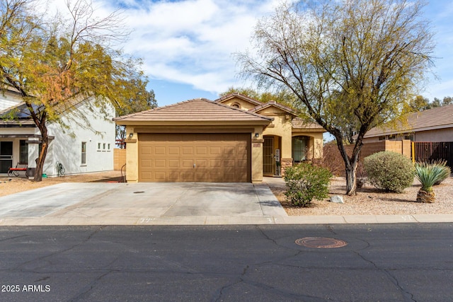 view of front facade featuring a tile roof, stucco siding, an attached garage, fence, and driveway