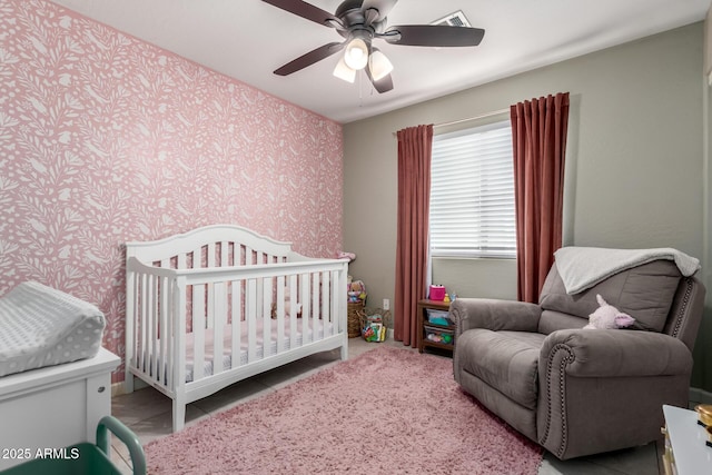 bedroom featuring wallpapered walls, a ceiling fan, visible vents, and a nursery area