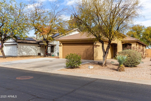 view of front of house featuring a garage, driveway, roof mounted solar panels, and stucco siding