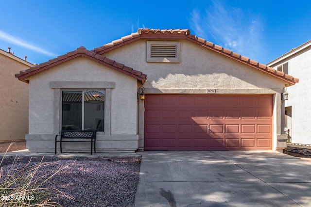 view of front facade with a garage, a tile roof, driveway, and stucco siding