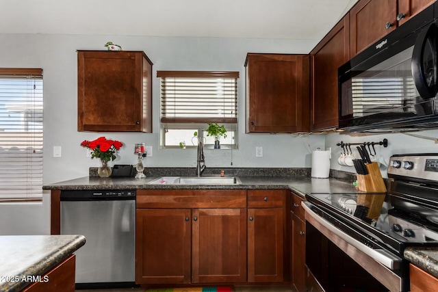 kitchen with appliances with stainless steel finishes, dark countertops, and a sink