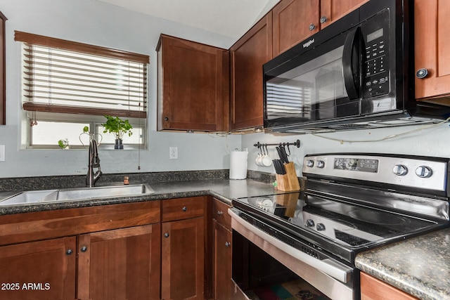 kitchen featuring black microwave, stainless steel electric range oven, dark countertops, and a sink