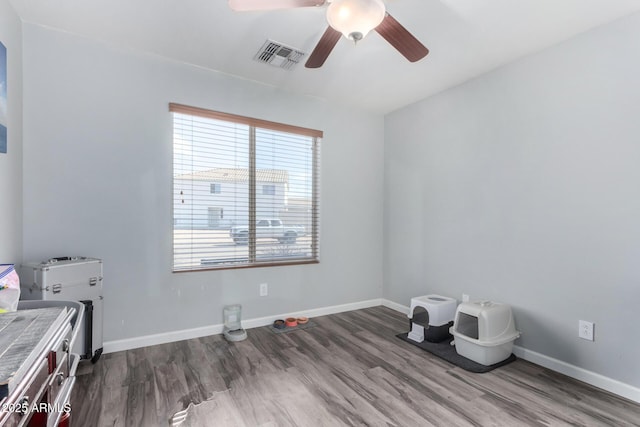 interior space with ceiling fan, wood finished floors, visible vents, and baseboards