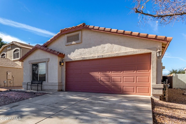 view of front of home featuring concrete driveway, a tile roof, an attached garage, and stucco siding