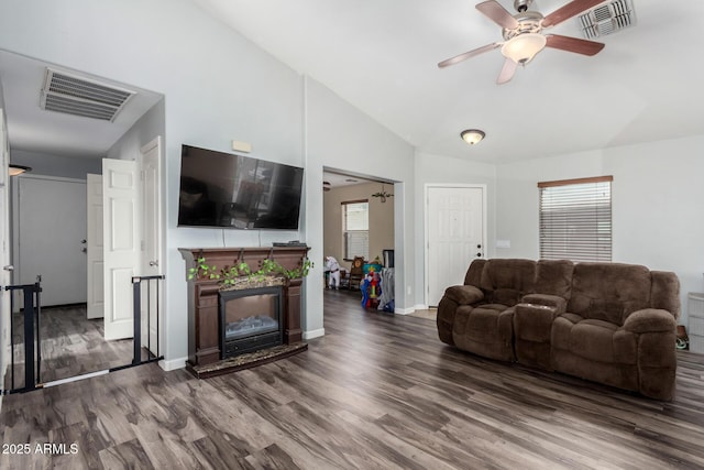 living area with a ceiling fan, visible vents, vaulted ceiling, and wood finished floors