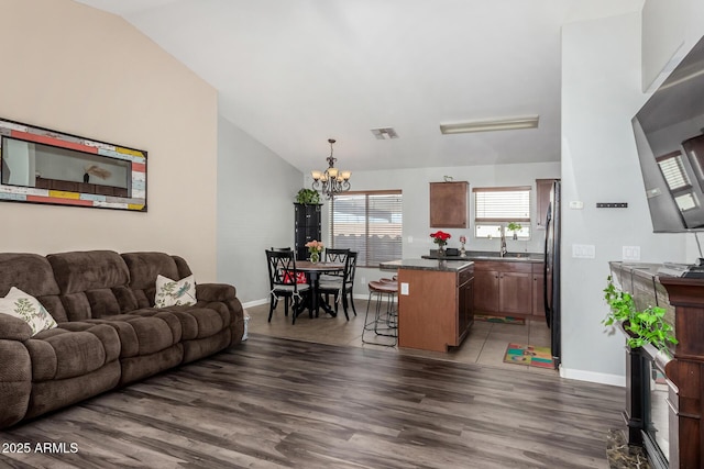 living room with lofted ceiling, dark wood-style floors, visible vents, and a chandelier