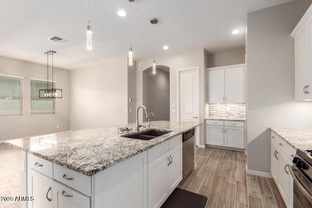 kitchen featuring white cabinetry, sink, and a center island with sink