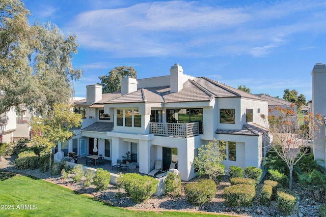 back of property with a lawn, a patio area, and a balcony