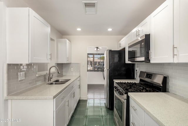 5635 N 35th Dr, Phoenix, AZ 85019 - kitchen featuring stainless steel appliances, a sink, baseboards, white cabinetry, and backsplash