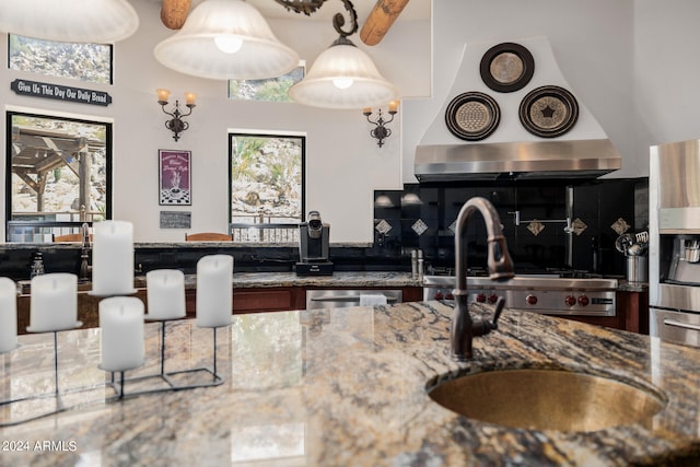 kitchen featuring stone countertops, plenty of natural light, sink, and range hood