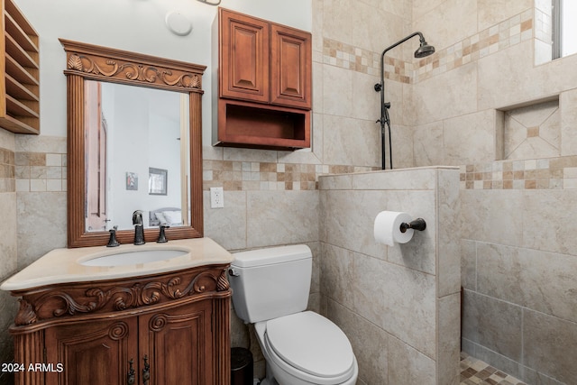 bathroom featuring toilet, vanity, tiled shower, and tile walls