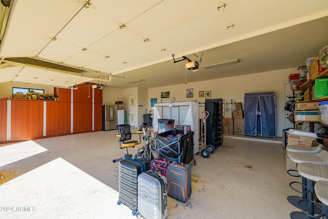 garage with a garage door opener and stainless steel fridge