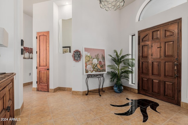 foyer featuring a towering ceiling, light tile patterned floors, and an inviting chandelier