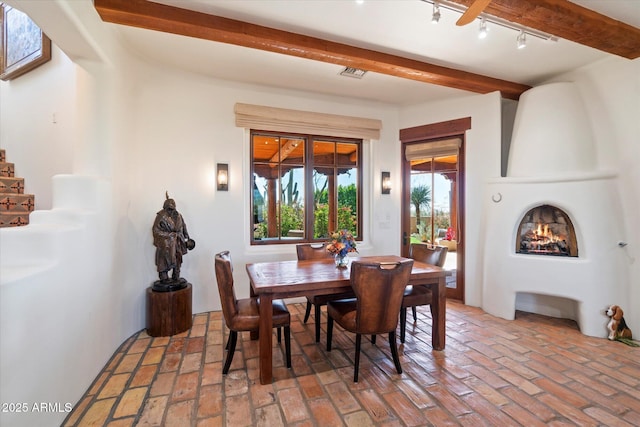 dining area with track lighting and a fireplace