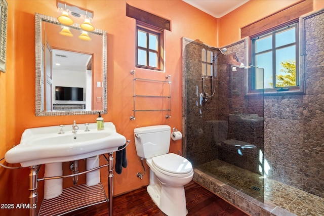 bathroom with hardwood / wood-style flooring, tiled shower, and toilet