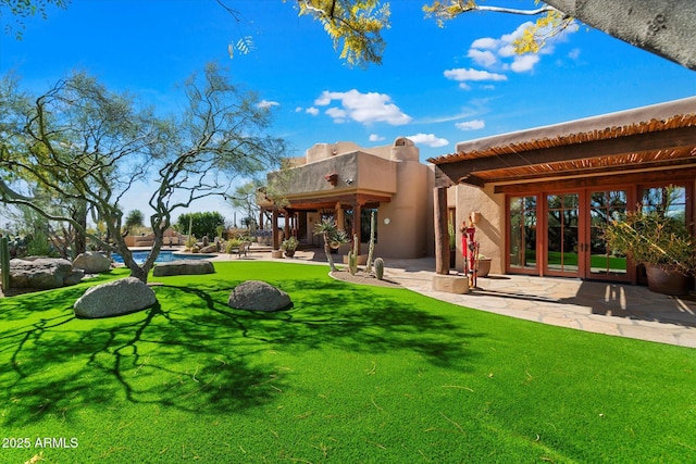 rear view of house with a patio, a lawn, and french doors