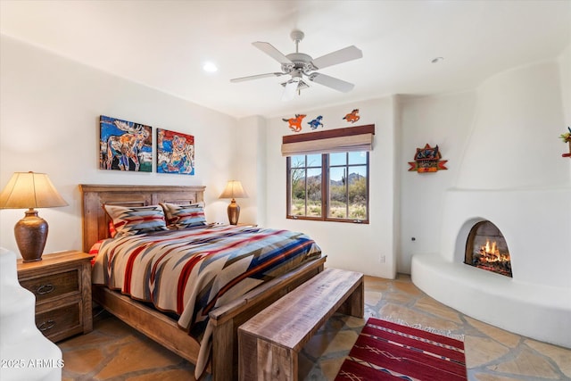 bedroom featuring a large fireplace and ceiling fan