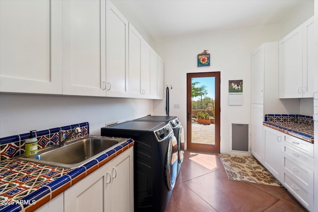 clothes washing area with sink, dark tile patterned floors, cabinets, and washing machine and clothes dryer