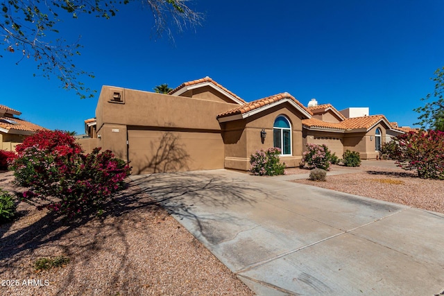 view of front facade featuring stucco siding, a tiled roof, driveway, and a garage