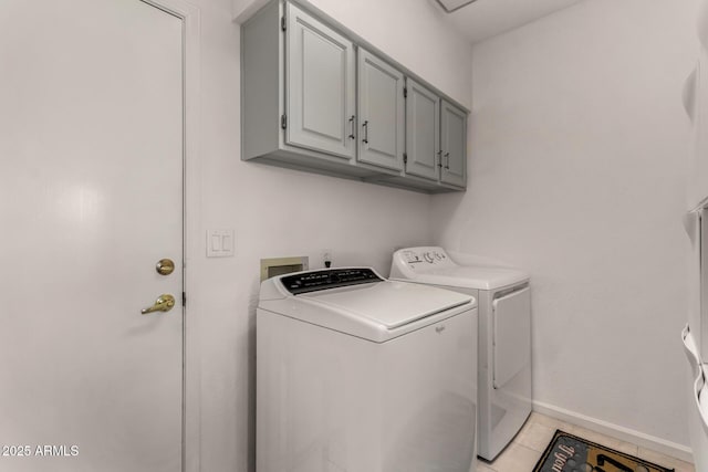 clothes washing area with light tile patterned flooring, cabinet space, baseboards, and washer and clothes dryer