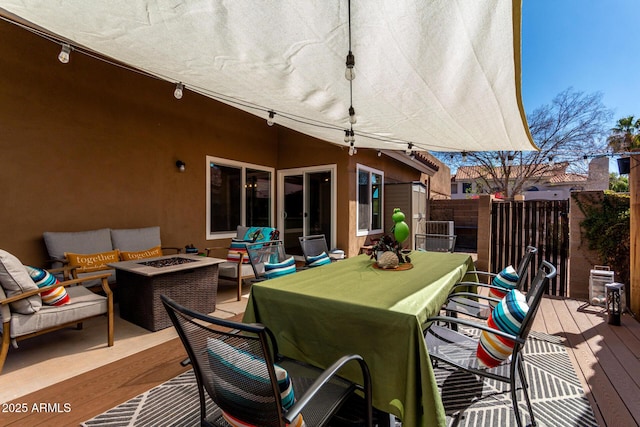 wooden deck with an outdoor living space with a fire pit, outdoor dining area, and fence