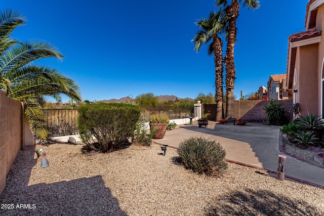 view of yard featuring a fenced backyard, a mountain view, and a patio