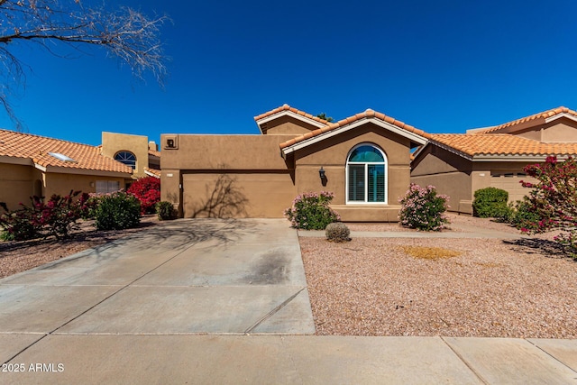 view of front of property featuring a tile roof, stucco siding, an attached garage, and concrete driveway