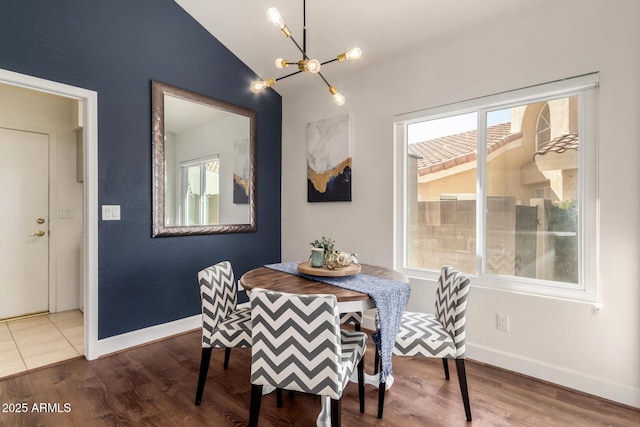 dining space with baseboards, an inviting chandelier, wood finished floors, and vaulted ceiling
