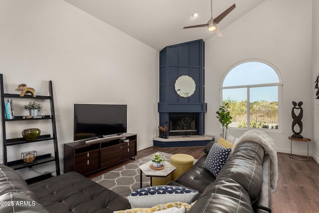 living room featuring high vaulted ceiling, wood finished floors, baseboards, and ceiling fan