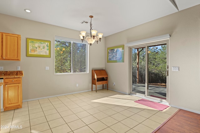 unfurnished room with a notable chandelier, a healthy amount of sunlight, and light tile patterned floors