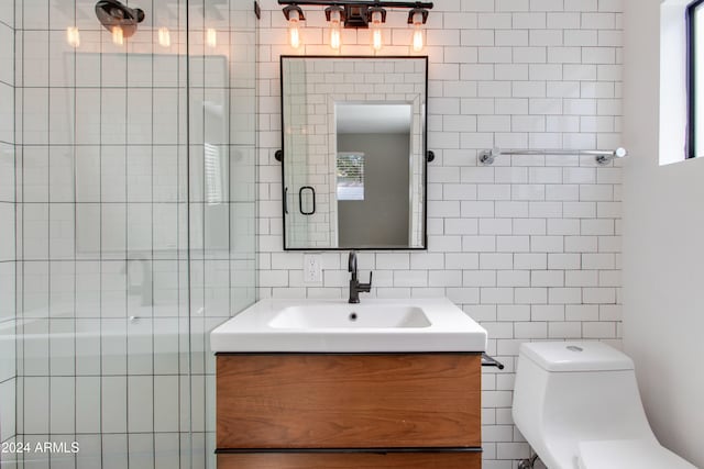 bathroom with a shower with door, vanity, toilet, and tile walls