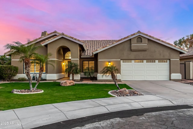 view of front facade with stucco siding, concrete driveway, and a front yard