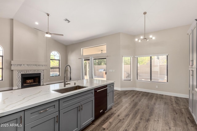 kitchen with dishwashing machine, open floor plan, gray cabinets, and a sink