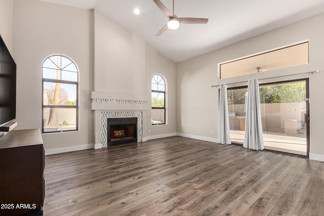 unfurnished living room with baseboards, a fireplace, wood finished floors, high vaulted ceiling, and a ceiling fan