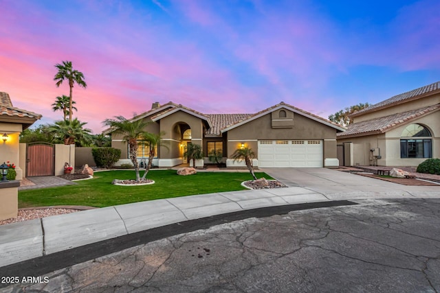 mediterranean / spanish home with a front yard, a gate, an attached garage, stucco siding, and concrete driveway