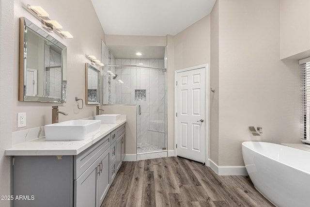 full bath featuring a freestanding tub, a stall shower, wood finished floors, and a sink