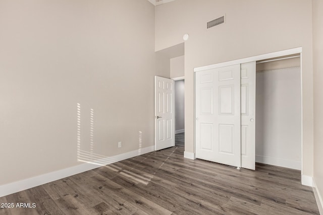 unfurnished bedroom with visible vents, baseboards, a closet, and wood finished floors