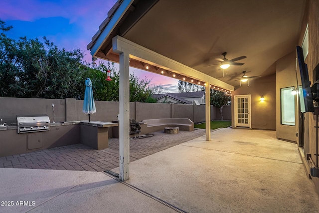 view of patio / terrace featuring a fire pit, a fenced backyard, area for grilling, an outdoor kitchen, and a ceiling fan