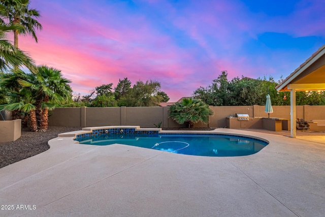 pool at dusk featuring exterior kitchen, a patio area, a fenced in pool, and a fenced backyard