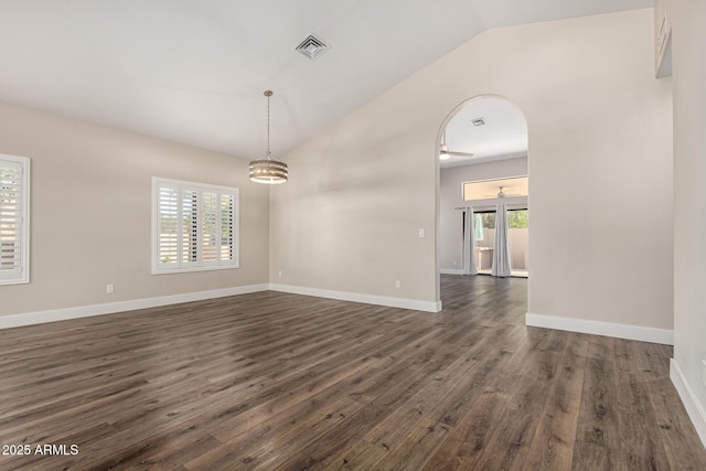 unfurnished room with baseboards, visible vents, lofted ceiling, arched walkways, and dark wood-type flooring