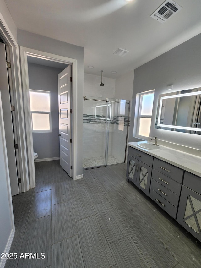 bathroom featuring vanity, a shower with shower door, and toilet