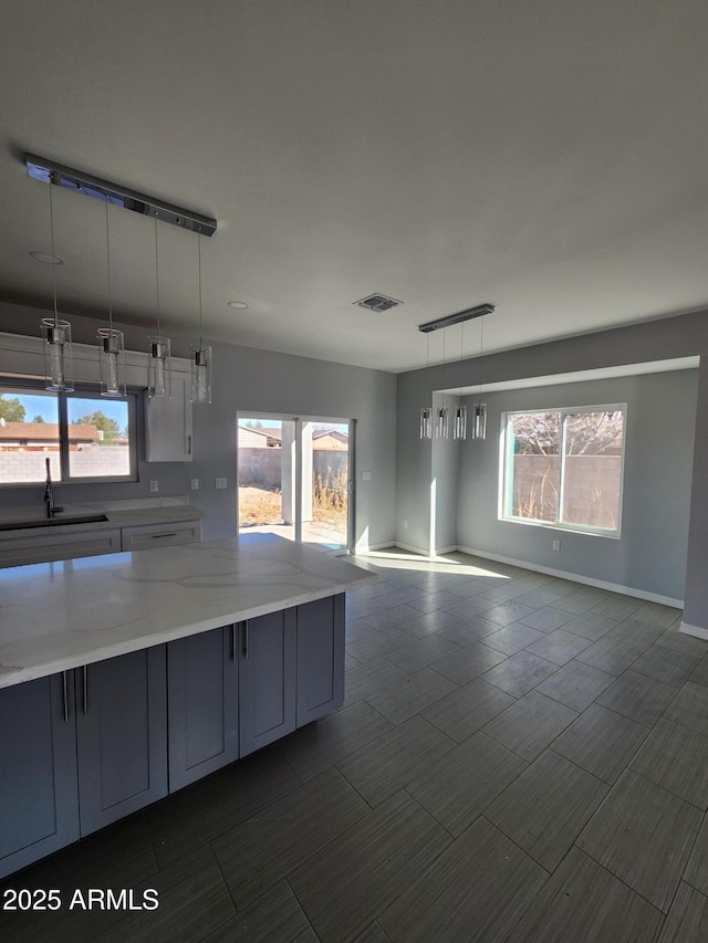 kitchen featuring pendant lighting, sink, and light stone counters