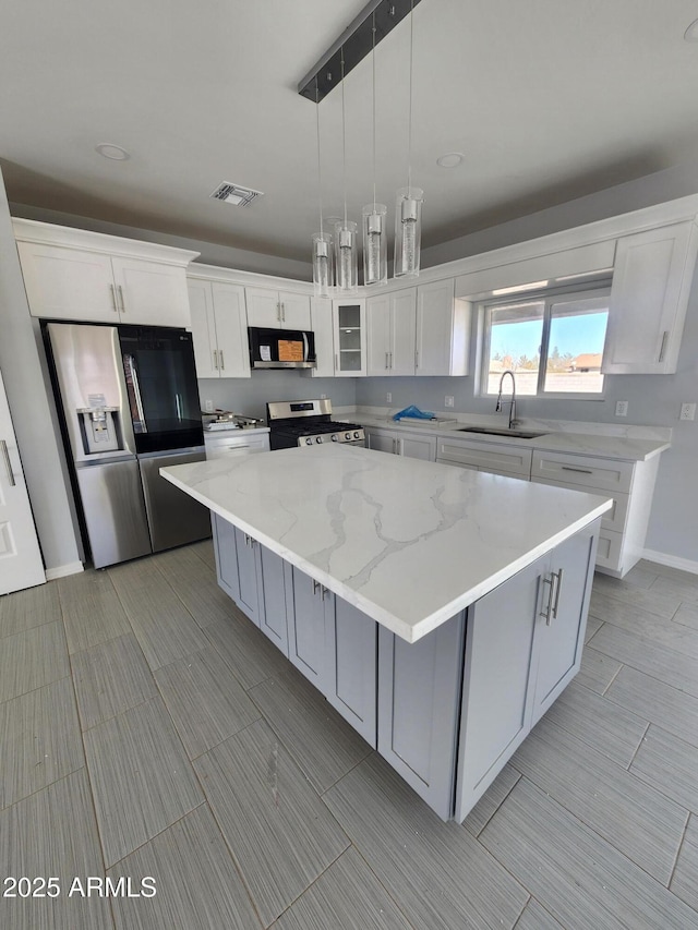 kitchen with stainless steel appliances, sink, a kitchen island, and white cabinets